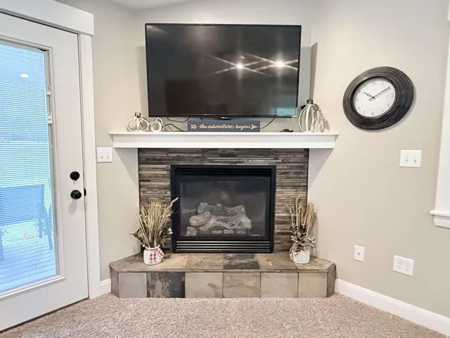 Built-in corner fireplace featuring a stacked stone surround and tile hearth