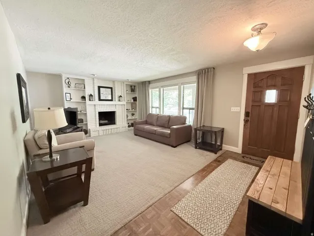 Brick fireplace with built-in shelving, wood-finish flooring, and a paneled entry door