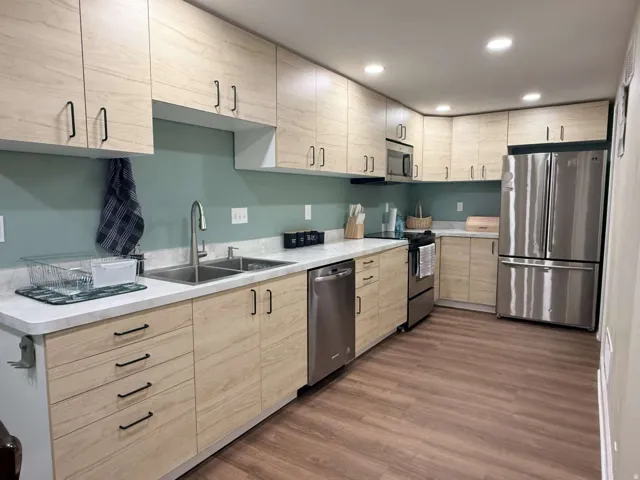 Full kitchen featuring wood-finish cabinetry, stainless steel appliances, white countertops, and wood-finish flooring