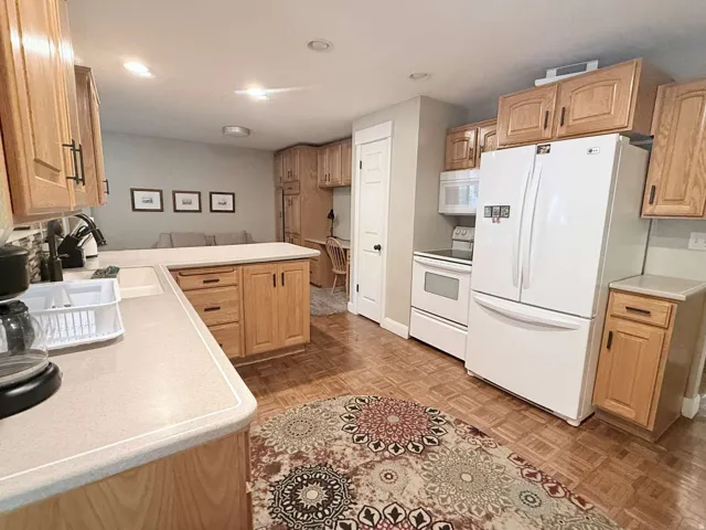 Wood-finish flooring, light wood cabinetry, and solid surface countertops