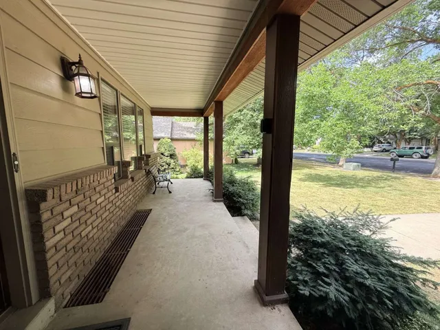 Covered front porch featuring a brick facade, siding, and wood-finish support columns