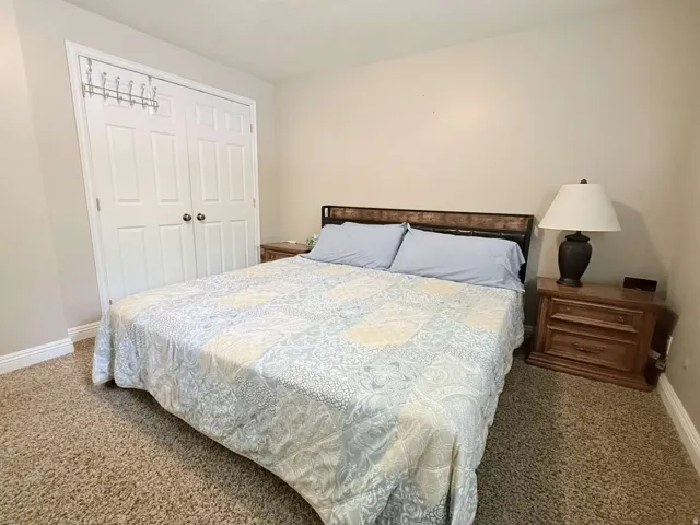 Double bi-fold closet doors, carpet flooring, and neutral wall paint