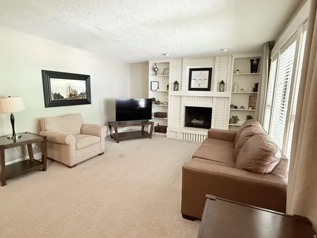 White brick fireplace with an integrated mantel, built-in shelving, and recessed lighting