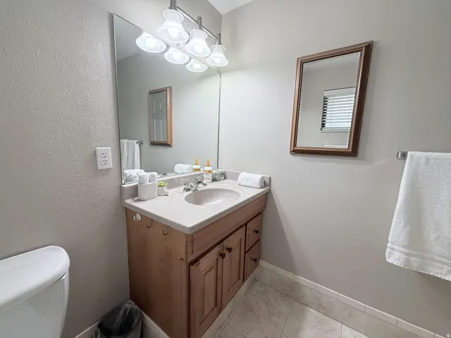 Wood-finish vanity with a single basin sink and light-colored countertop