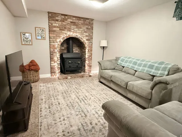 Exposed brick fireplace with an arched opening, featuring a black wood-burning stove