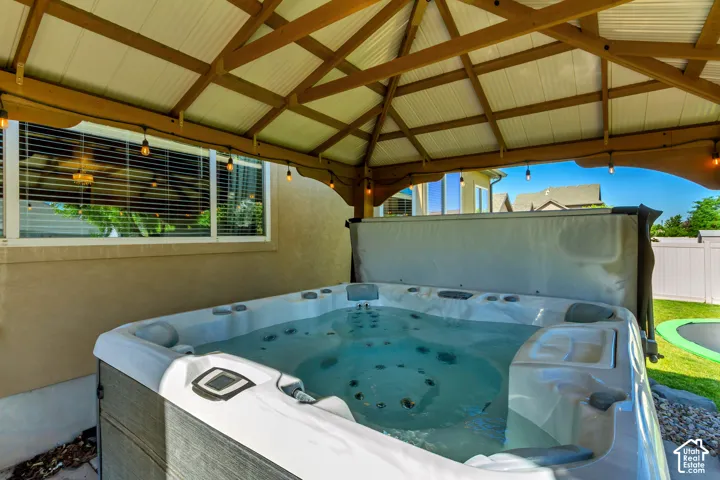 Covered outdoor spa with a wooden pergola and string lighting