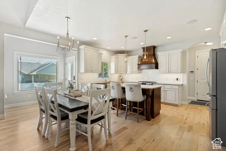 Open-concept kitchen and dining area featuring light wood-finish flooring, a kitchen island with seating, pendant lighting, and recessed ceiling lights