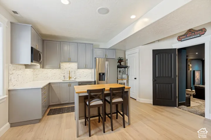 L-shaped kitchen with shaker-style cabinetry, stainless steel appliances, light wood-finish flooring, and recessed lighting