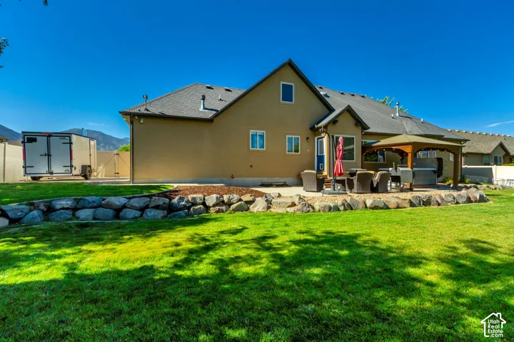 Expansive lawn with a retaining wall, a paved patio, and a covered outdoor structure