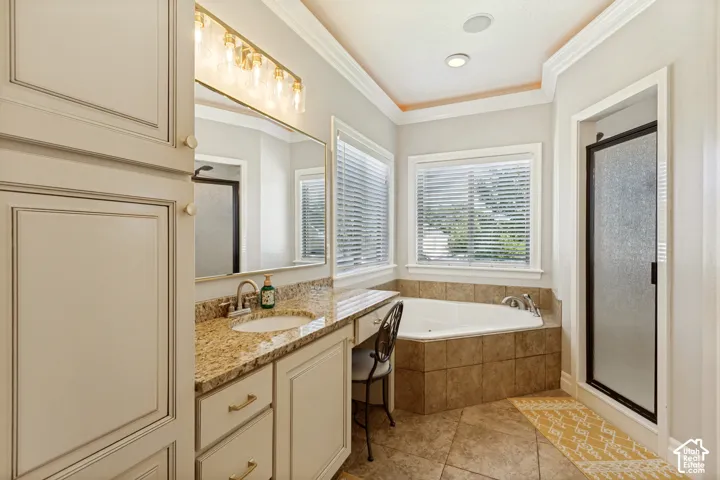 Spa-inspired primary bathroom featuring dual vanities with granite countertops, an undermount soaking tub with tile surround, recessed lighting, and abundant natural light from multiple windows