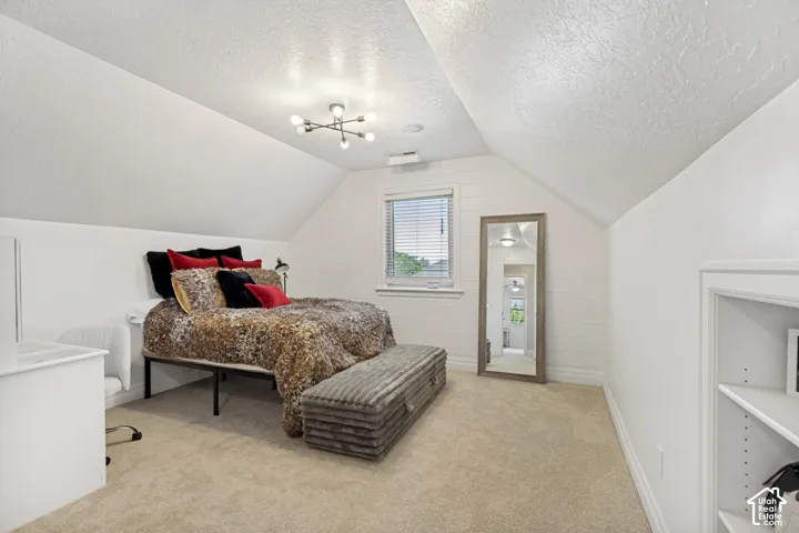 Bedroom featuring sloped ceilings, a window with blinds, carpet flooring, a built-in shelving unit, and a contemporary ceiling light fixture
