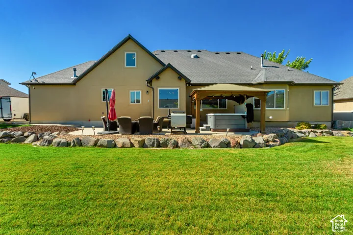 Expansive green lawn with a rock-lined border leading to a paved patio area