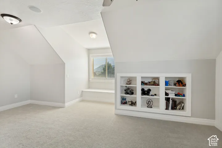 Carpeted flooring, built-in shelving, window with blinds, recessed ceiling lighting, and sloped ceiling