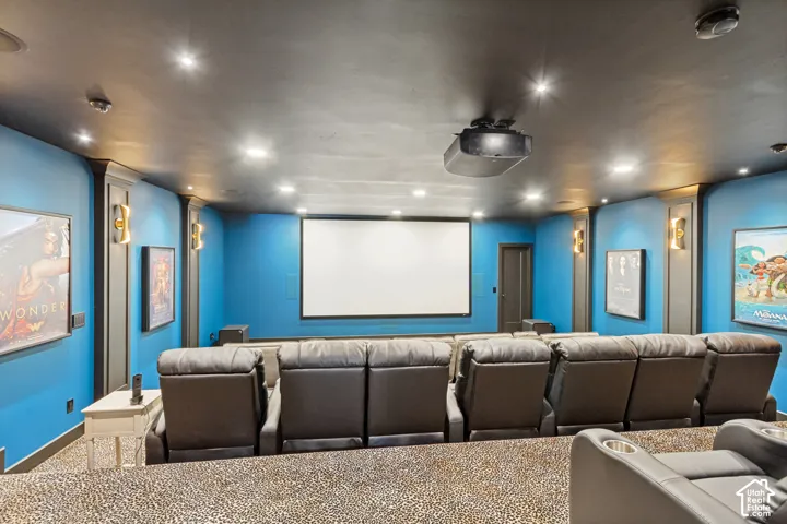 Dedicated media room featuring a large projection screen, recessed lighting, and wall-mounted sconces