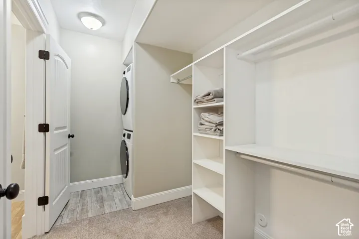 Integrated stacked laundry appliances, built-in shelving, white trim, and neutral carpeting
