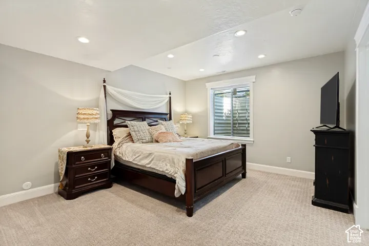Recessed ceiling lighting, vaulted ceiling, neutral wall color, carpeted flooring, and a white-trimmed window