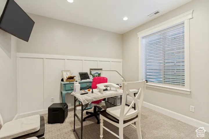 Wall-mounted television, recessed lighting, accent wall with paneling, window with blinds, and carpeted flooring
