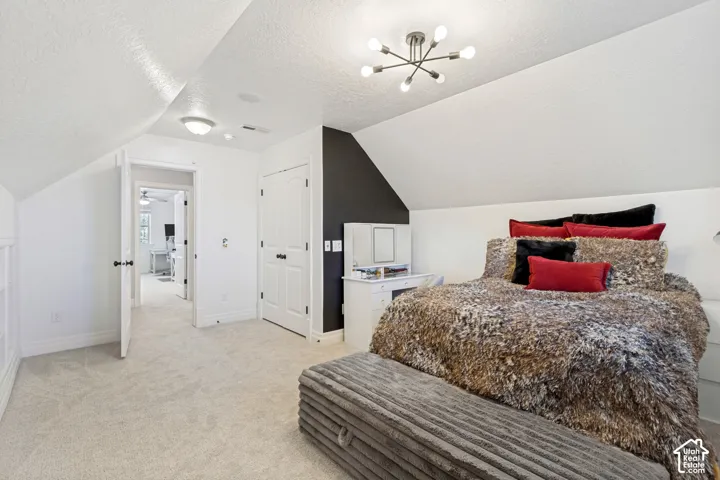 Sloped ceiling with recessed lighting, plush carpet flooring, built-in closet with white paneled door, and a modern Sputnik-style ceiling fixture