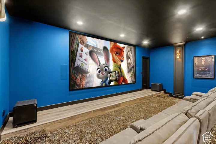 Dedicated media room featuring a large projection screen, recessed ceiling lights, and wall sconces