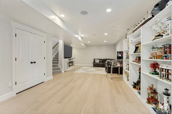 Recessed lighting, wood-finish flooring, built-in shelving, white trim, and a built-in electric fireplace