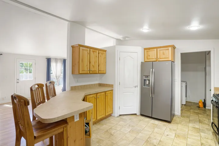 Kitchen featuring wood cabinetry, stone-finish countertops, stainless steel refrigerator, and recessed lighting
