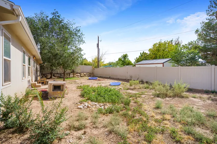 Expansive backyard with a privacy fence, mature trees, and a detached shed