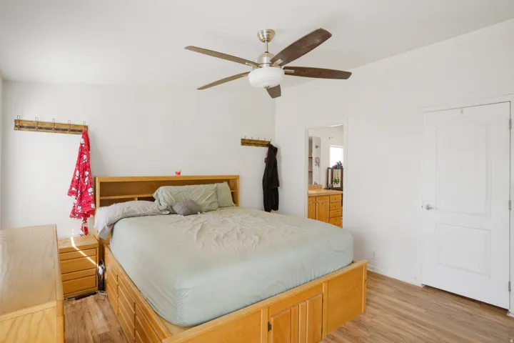 Wood-finish flooring with a ceiling fan light fixture and a multi-panel door