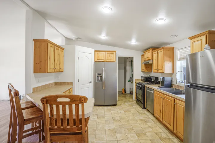 Kitchen featuring recessed lighting, a built-in breakfast bar, stainless steel appliances, wood cabinetry, and tiled flooring