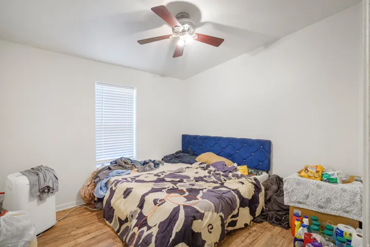 Wood-finish flooring, white walls, and a ceiling fan with integrated lighting