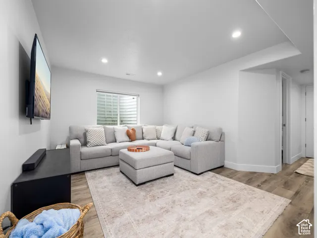 Recessed lighting, wood-finish flooring, white walls, and a built-in window with horizontal blinds