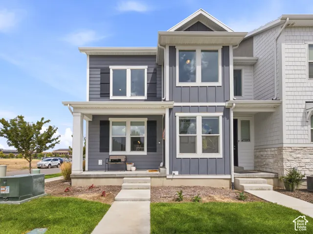 Two-story exterior with horizontal and vertical siding, covered front porch with white columns, and dark shutters on select windows