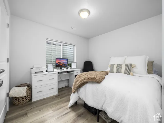 Light wood-finish flooring, white walls, and a built-in desk with white cabinetry
