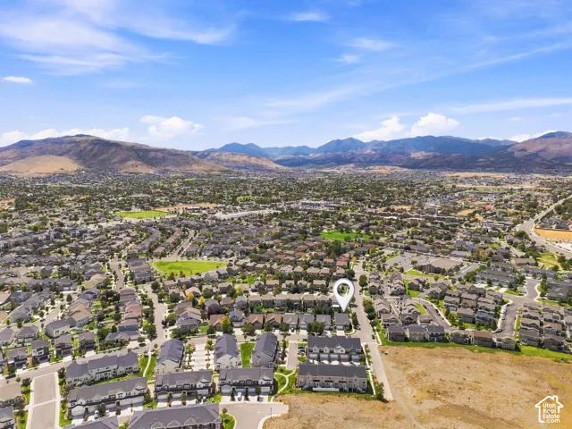 Expansive residential area with a mountain backdrop, featuring numerous single-family homes and townhomes, and a clear blue sky