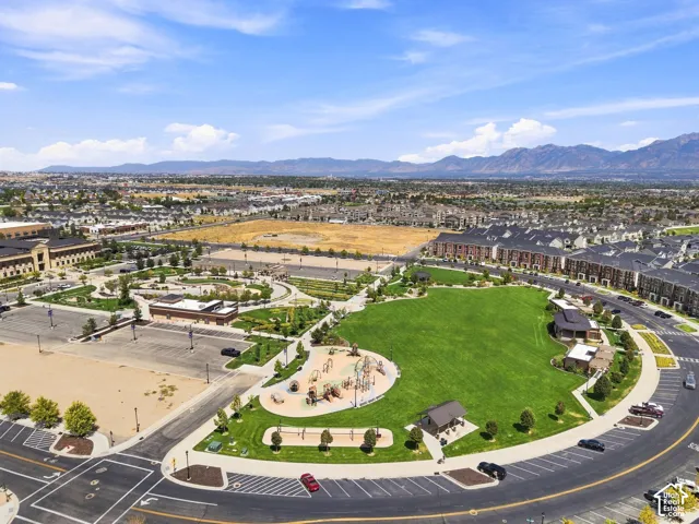 Expansive green space, multi-structure playground, mountain backdrop, surrounding townhomes, paved parking areas