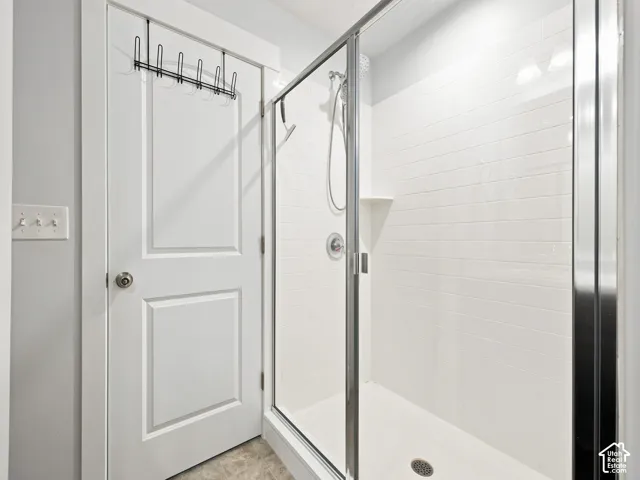 Glass-enclosed shower featuring white subway tile, a built-in corner shelf, and a chrome shower fixture