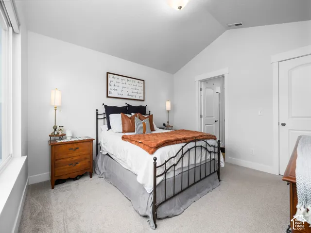 Vaulted ceiling with an overhead light fixture, light gray carpet flooring, white painted walls, and white trim work