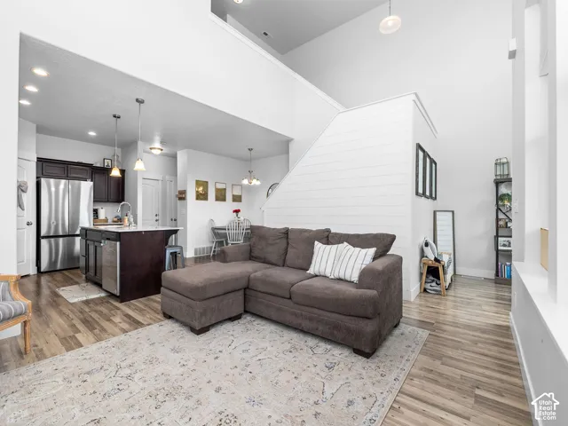 Open-concept living space featuring wood-finish flooring, a kitchen island with seating, stainless steel appliances, and high ceilings