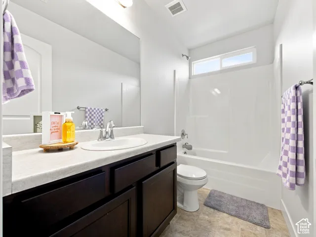 White sink basin with chrome faucet, dark wood-finish vanity, light-toned countertop, white bathtub/shower combination, and a window above the shower
