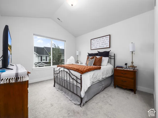 Vaulted ceiling, plush carpeting, large window, and recessed lighting