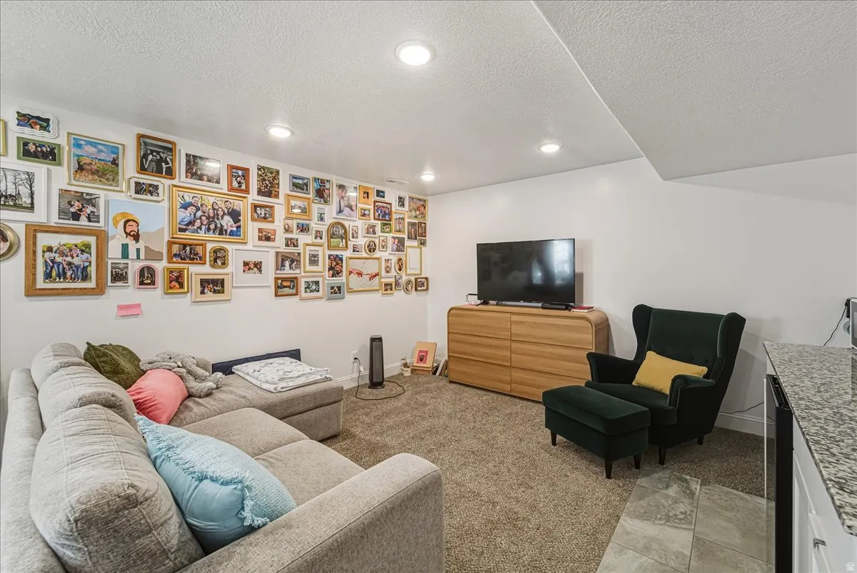 Recessed ceiling lighting, textured carpet flooring, white painted walls, and granite-style countertop