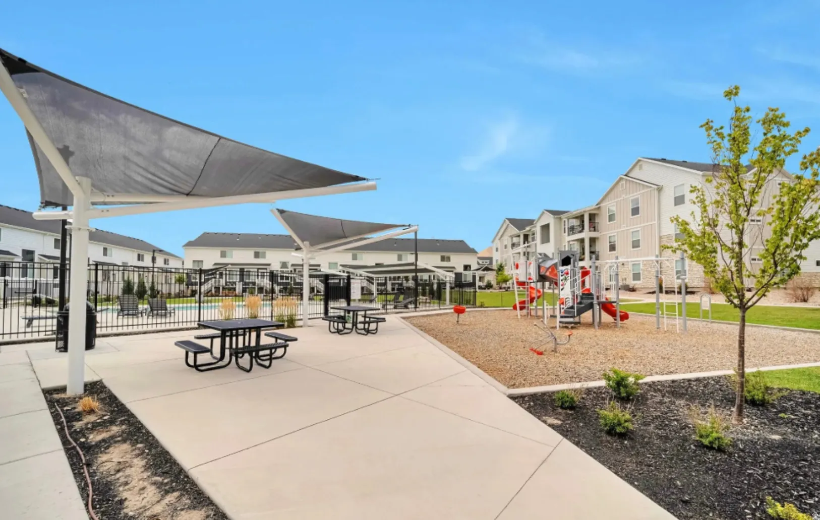 Community playground with a sand base, shade structures, and picnic tables