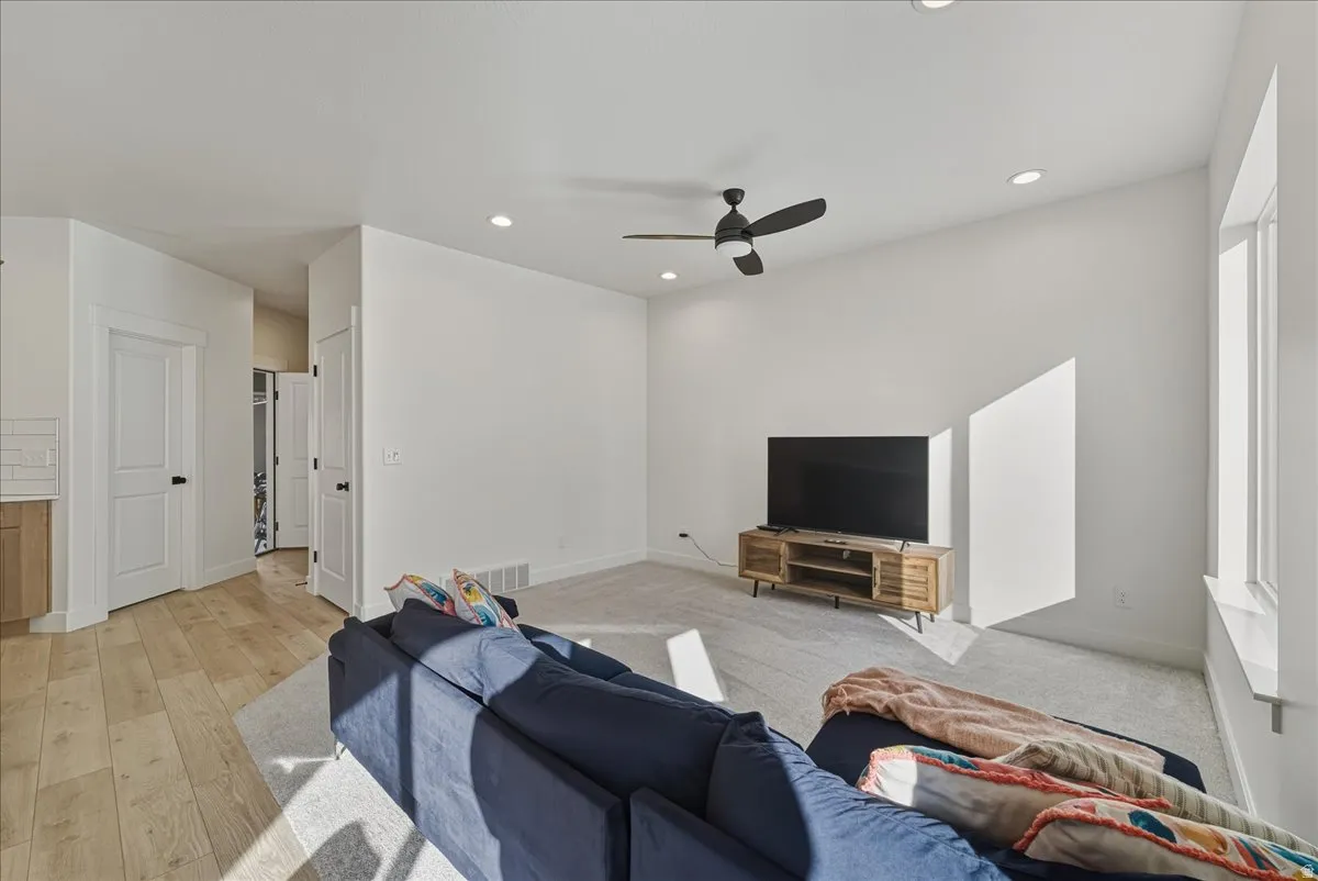 Recessed lighting, ceiling fan, wood-finish flooring, white doors, and carpeted area
