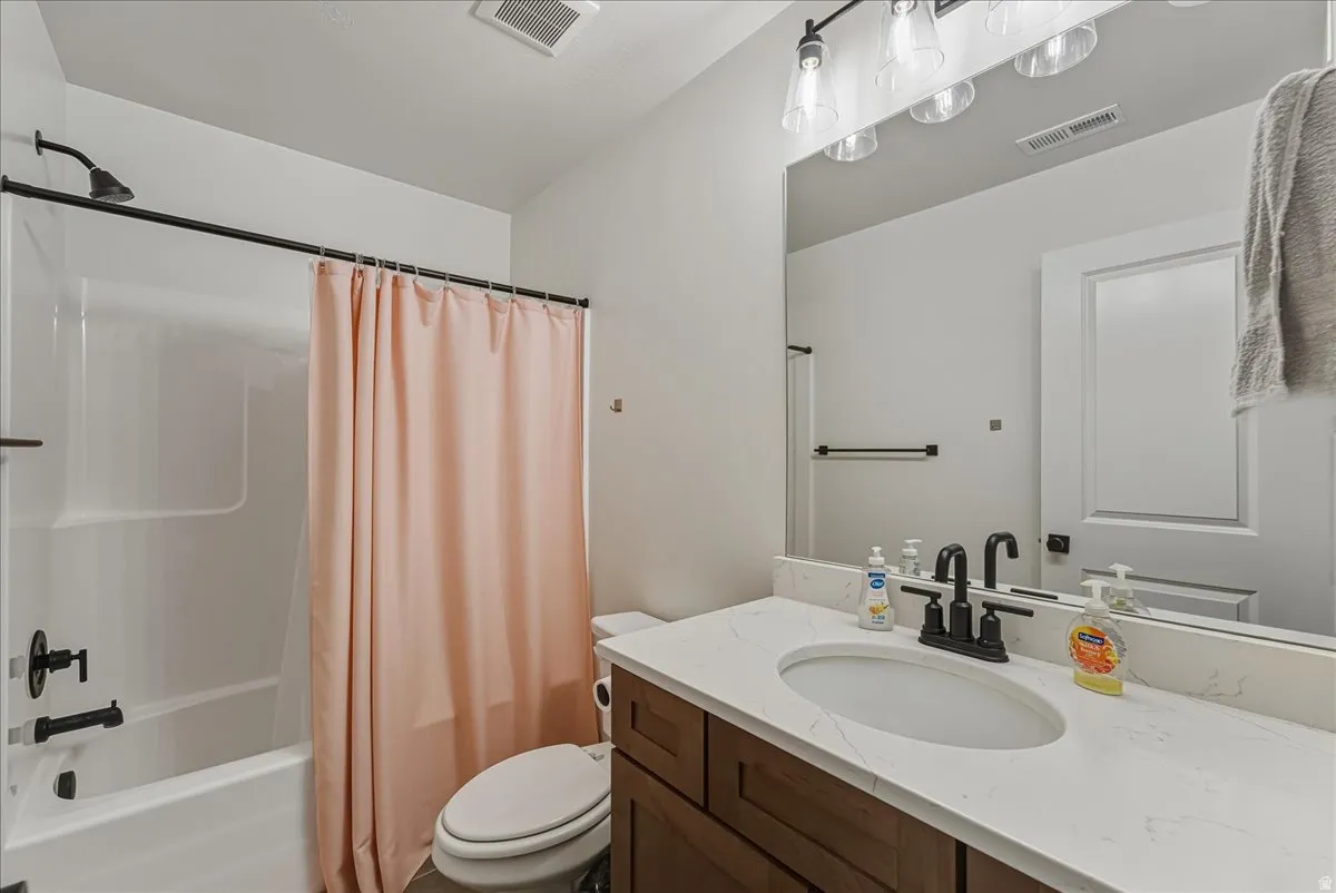 Bathroom featuring a white bathtub, dark bronze fixtures, a vanity with wood-finish cabinetry, a large mirror, and a white countertop