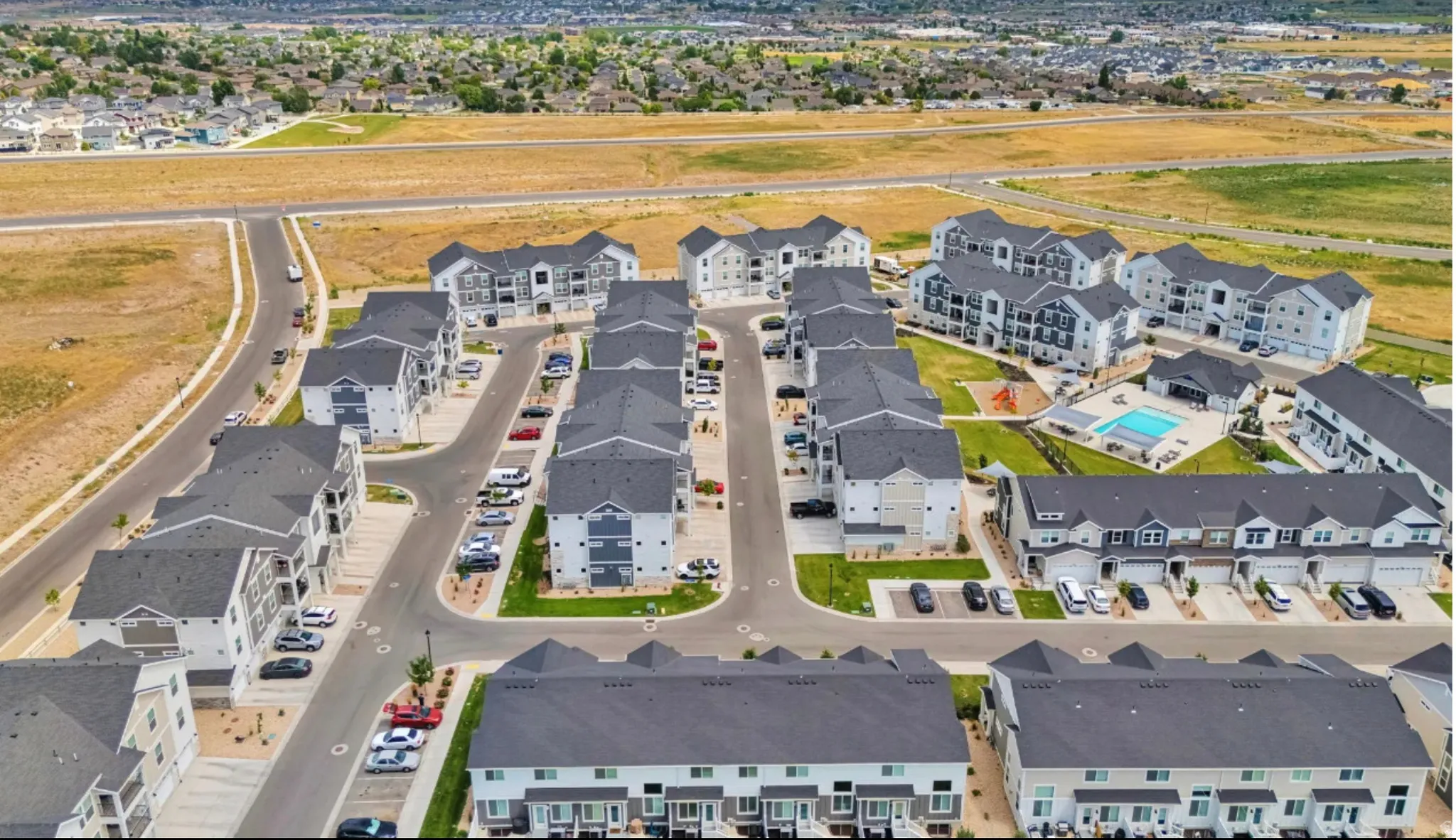 Community setting featuring multi-story residential buildings, paved roadways, and integrated parking