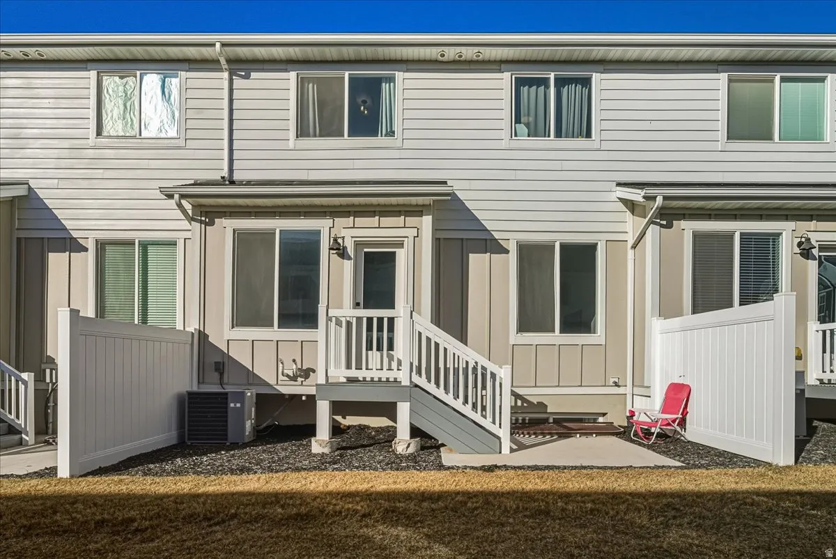 Two-story exterior with horizontal siding, individual rear patios, and white vinyl privacy fencing