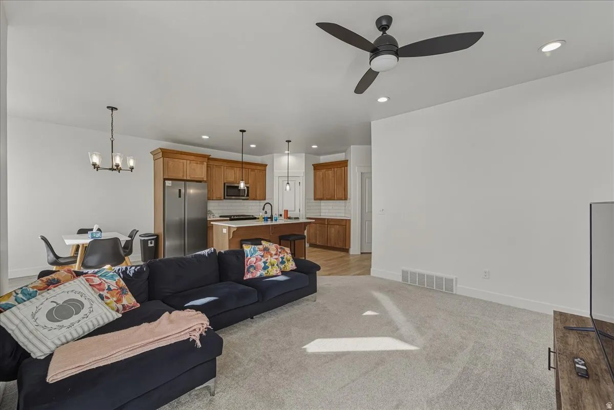 Open-concept living space featuring a ceiling fan, recessed lighting, and light-colored carpeting