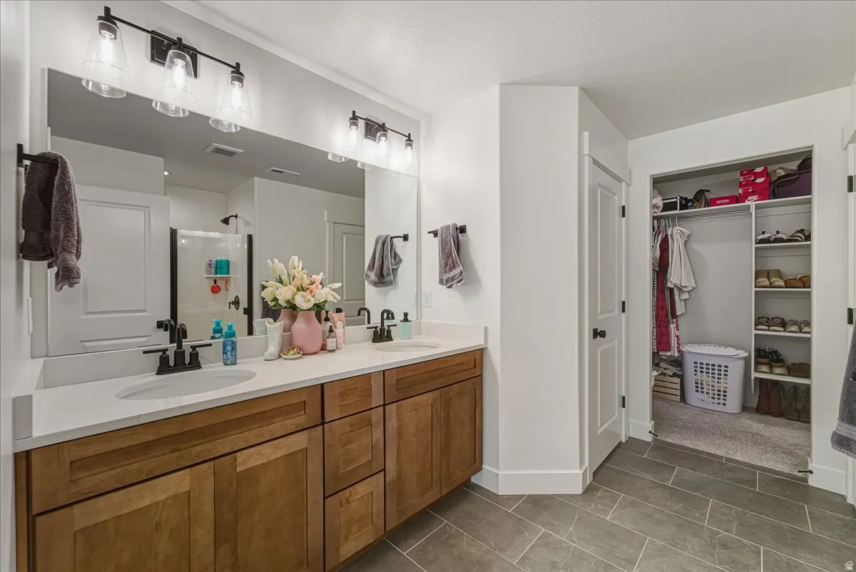 Dual vanity with wood-finish cabinetry, white countertop, and integrated sinks