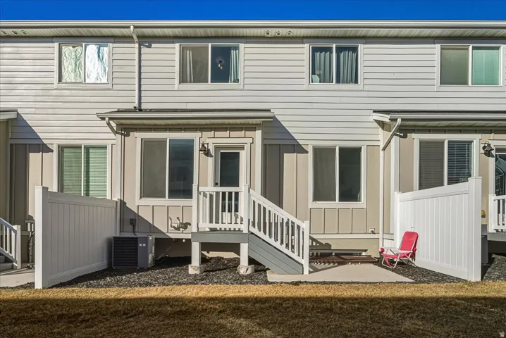Two-story exterior with horizontal siding, individual rear patios, and white vinyl privacy fencing