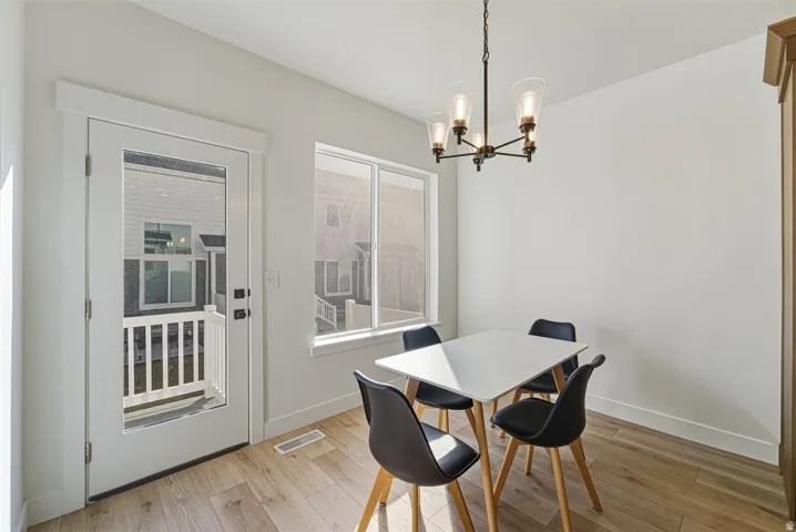 Wood-finish flooring, white walls, and a contemporary chandelier