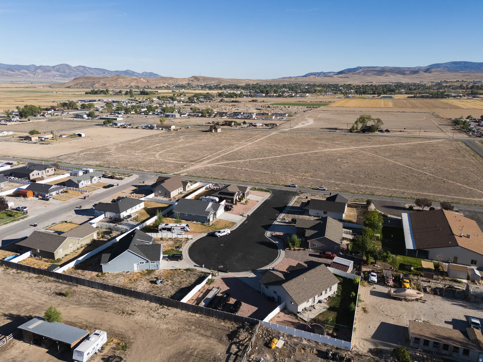 Cul-de-sac street with single-story residences, surrounded by open land and distant mountains